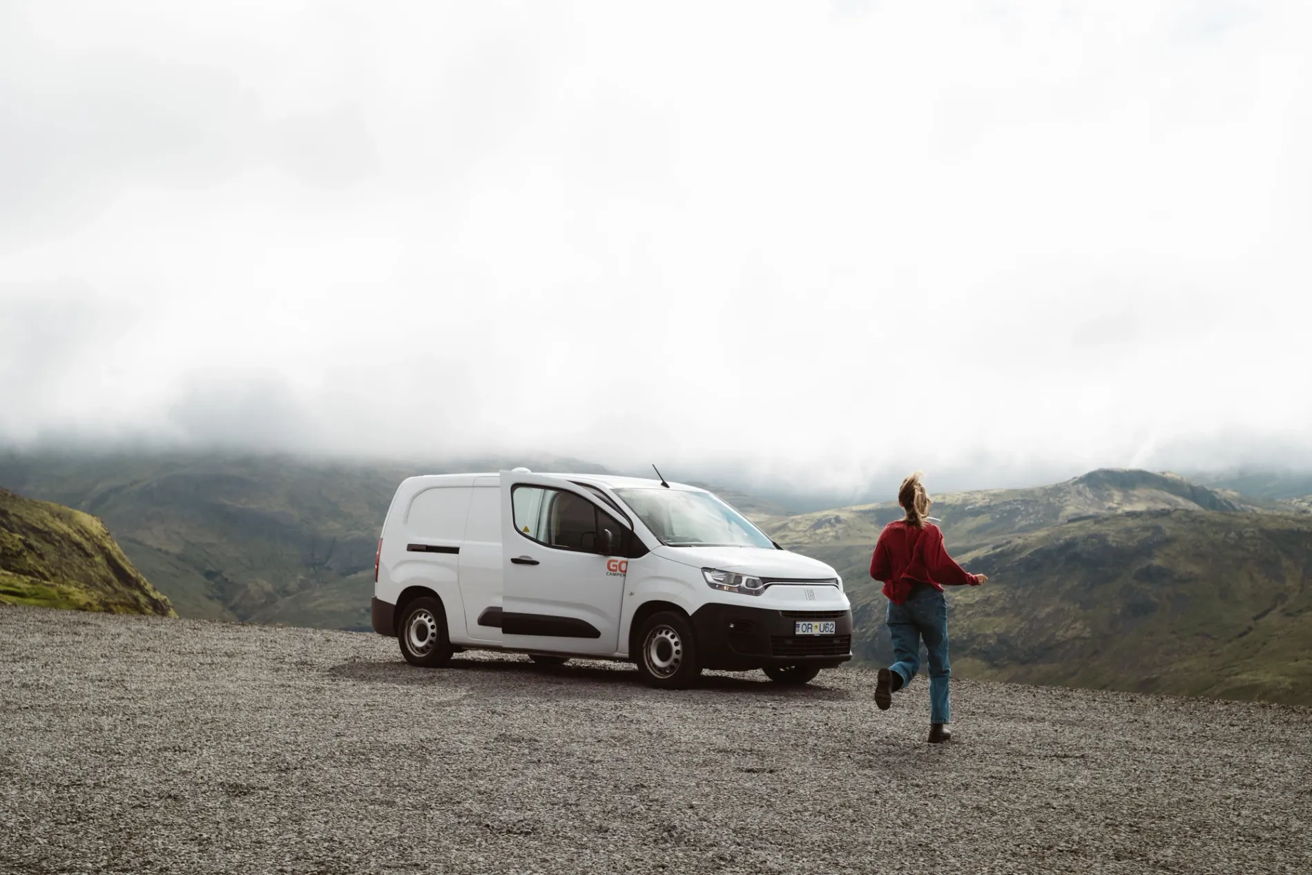 Traveller beside a white Go Campers campervan at a mountain viewpoint in Iceland